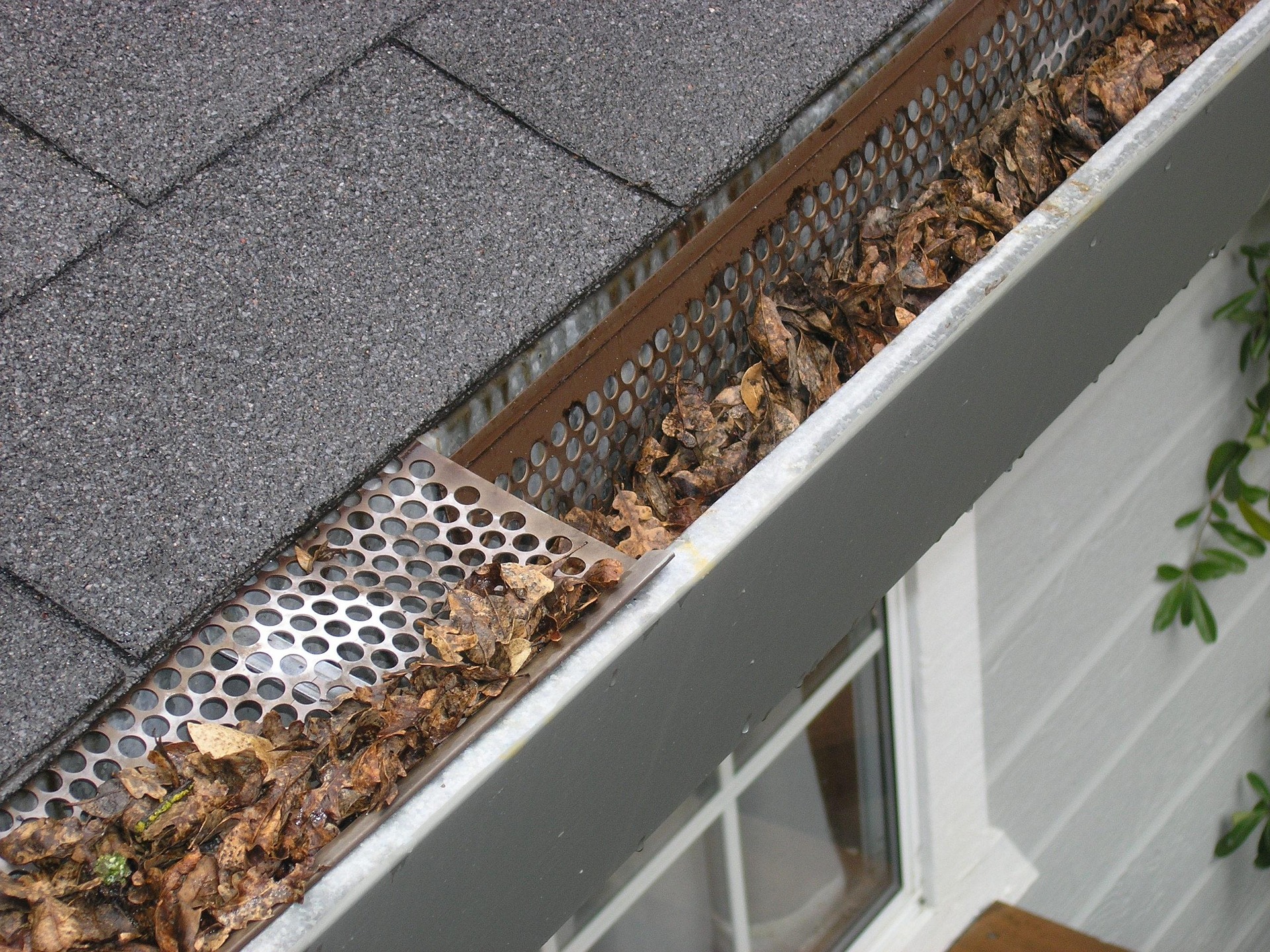 Metal gutter on a house being cleaned with a leaf blower